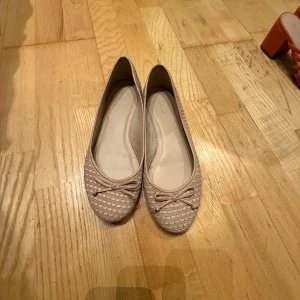 Beige ballerinaskor från Arezzo - Säljer ett par eleganta beige ballerinaskor från Arezzo. Skorna har en fin rosett på ovansidan och ett diskret mönster som ger dem en unik touch. Perfekta för en stilren look. kom gärna med prisförslag🥰🥰