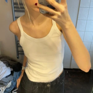 Vit linnetopp - Säljer en stilren vit linnetopp med breda axelband. Perfekt för en enkel och avslappnad look. Passar bra till jeans eller shorts. storlek L men sitter som S eller M