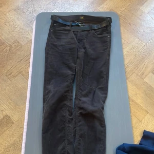 Bruna manchesterbyxor från Lee - Snygga bruna manchesterbyxor från Lee med ett medföljande svart bälte. Byxorna har en klassisk design med fem fickor och nitar vid fickorna för extra hållbarhet. Perfekta för en stilren look.