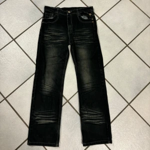 Svarta jeans med detaljer - Snygga svarta jeans med coola detaljer och slitningar. De har en klassisk femficksdesign och en knappgylf. Perfekta för en avslappnad stil.