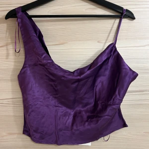 Lila sidenlinne från Zara - Snyggt lila sidenlinne från Zara med smala axelband varav det ena går att ändra längden på. Behöver strykas då den legat i garderoben ett tag. Helt ny med lappen kvar, har bara inte kommit till användning!!
