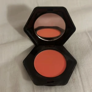 Korallfärgad rouge från H&M - Snygg korallfärgad rouge i en sexkantig kompakt från H&M. Perfekt för att ge kinderna en fräsch och livfull färg. Kommer med en inbyggd spegel för enkel applicering när du är på språng.