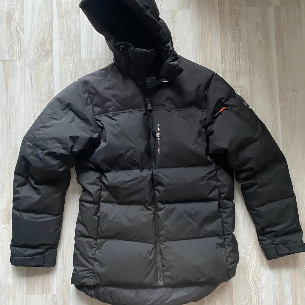 Hej, Svart Sail Racing Antarctica jacka med huva i strl Medium. Jackan har en ficka på bröstet och två fickor på sidorna. Jackan har en logga på vänster ärm. Den är i väldigt bra skick!. Takit.