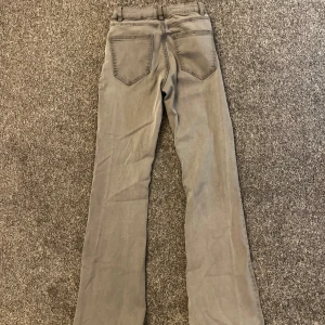 Grå byxor från Lindex - Snygga grå byxor från Lindex med en klassisk design. Byxorna har en rak passform och är perfekta för en stilren look. De har fickor både fram och bak samt hällor för bälte. Flare jeans.