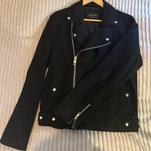 Svart jacka från River Island - Jacka från River Island med en dragkedja på sidan, silver detaljer. Storlek M, pris kan diskuteras, säljer åt min pappa