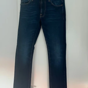 Mörkblå jeans från Nudie Jeans - Snygga mörkblå jeans från Nudie Jeans i modellen Lean Dean st W30. L32.Tillverkade av ekologisk bomull med en klassisk femficksdesign och orange sömmar. Perfekta för en stilren look. Nypris 1500 kr, nu 750 kr! 
