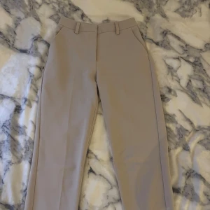 Beige kostymbyxor - Beige kostymbyxor fickor på sidorna, fejkfickor baktill. Köpt på NA-KD och bra skick