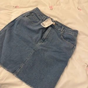 Blå jeanskjol från H&M - Snygg blå jeanskjol från H&M med klassisk femficksdesign. Kjolen har en rå kant nertill för en trendig look. Perfekt för en avslappnad stil. 🦋