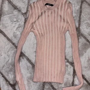 Rosa ribbad tröja från Bik Bok - Säljer en stilren rosa ribbad tröja från Bik Bok. Tröjan har en tight passform och långa ärmar, perfekt för lager-på-lager under kyligare dagar. Den mjuka rosa färgen gör den lätt att matcha med olika outfits. Perfekt för både vardag och lite finare tillfällen.