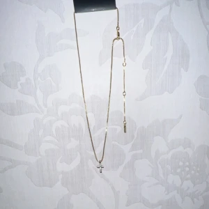 Guldhalsband med kors - Elegant guldhalsband med ett litet korshänge. Kedjan är tunn och smidig, vilket ger ett stilrent intryck. Perfekt för att lägga till en subtil touch av elegans till din outfit.