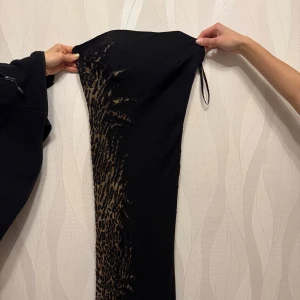 Svart klänning med leopardmönster - Elegant svart klänning med leopardmönster på sidan. Utan band och med dragkedja där bak och vaddering för brösten. Pris kan diskuteras och kom privat för fler bilder. Storlek 36/38 passar s/m 
