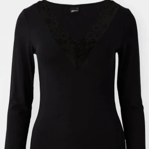 Svart långärmad topp med spetsdetaljer - Elegant svart långärmad topp från Gina Tricot med v-ringad spetsdetalj. Perfekt för en stilren look.