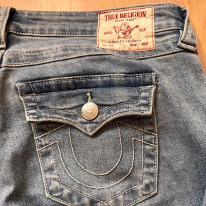 True religion jeans joey -  Jätte snygga ljusblå jeans från True Religion med låg midja och flare-stil. De har en klassisk femficksdesign med knappar och en broderad detalj. Köpta här på plick, säljer pga att de inte passade mig tyvärr. Midjemått- 42cm tvärs över, Innerbenslängd- 80cm. Inga defekter 💛 Tidigare ägare har bara använt ett fåtal ggr.