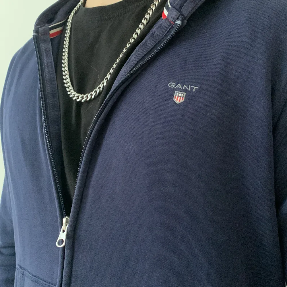 Säljer en stilren mörkblå Gant hoodie med dragkedja. Tröjan är  storlek Xs och är för liten för mig som är 168 cm lång. Inga tecken på användning och varken defekter heller. Mitt pris 250kr hör gärna av dig om du har frågor eller är intresserad hälsningar Alex . Hupparit & Collegepaidat.