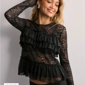 Svart spetsblus med volanger Nelly - Snygg svart spetsblus från Nelly med volanger framtill. Blusen är genomskinlig och har långa ärmar, perfekt för tex festligheter. Sprillans ny med lapp fortfarande på. Säljs då den helt enkelt ej kommit till användning, men sjukt snygg på har bara inte fått ett tillfälle. Köptes ny för 400 Kr. Priset kan diskuteras vid snabb affär❤️