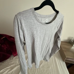 Grå långärmad tröja - Säljer en enkel och stilren grå långärmad tröja. Perfekt för en avslappnad look. Tröjan har en rund halsringning och är gjord i ett mjukt material. Andvänt bara 1 gång o kastat i gaderobben. Den är feån cubus