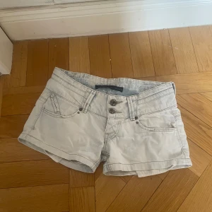 lowwaist Ljusblå shorts - Snygga shorts med två knappar framtill och fickor både fram och bak. Perfekta för en avslappnad stil. De har en lågmidjad design och är gjorda i ett bekvämt material.
