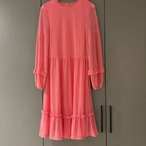 Rosa långklänning med volangdetaljer - Rosa klänning med volangdetaljer på ärmar och nederkant. 