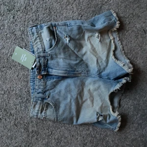 Blå jeansshorts - Snygga blå jeansshorts med slitna detaljer ifrån hm med lappen kvar! Perfekta till sommaren eller våren.