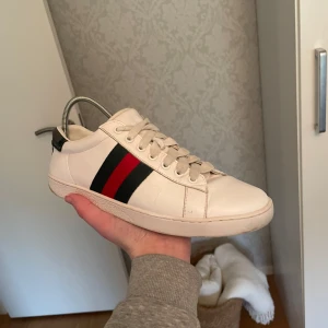 Gucci ace skor - Snygga vita sneakers med klassiska ränder i rött och grönt på sidan från gucci. Skorna har snörning och är tillverkade i skinn. Perfekta för en stilren look. Otroligt populära just nu!