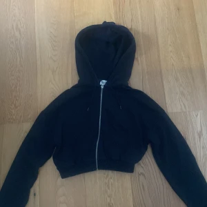 Svart hoodie från NA-KD Reborn - Säljer en snygg och bekväm svart hoodie från NA-KD Reborn. Den har en dragkedja framtill och en mysig huva. Perfekt för en casual look eller att mysa i hemma. Tillverkad i Turkiet och i storlek XS.