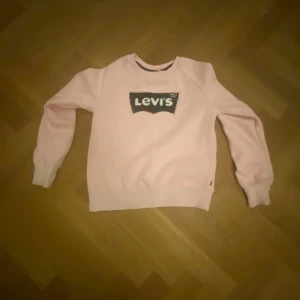 Rosa tjocktröja från Levis - Rosa tjocktröja med en liten fläck på ena ärmen 