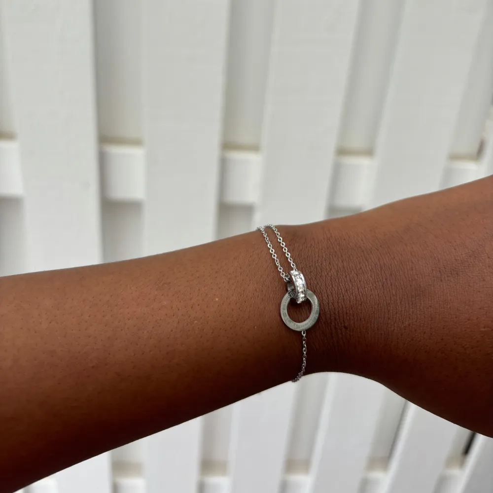 Elegant silver armband med en unik cirkulär detalj, tillverkat i rostfritt stål och justerbart för perfekt passform.. Asusteet.