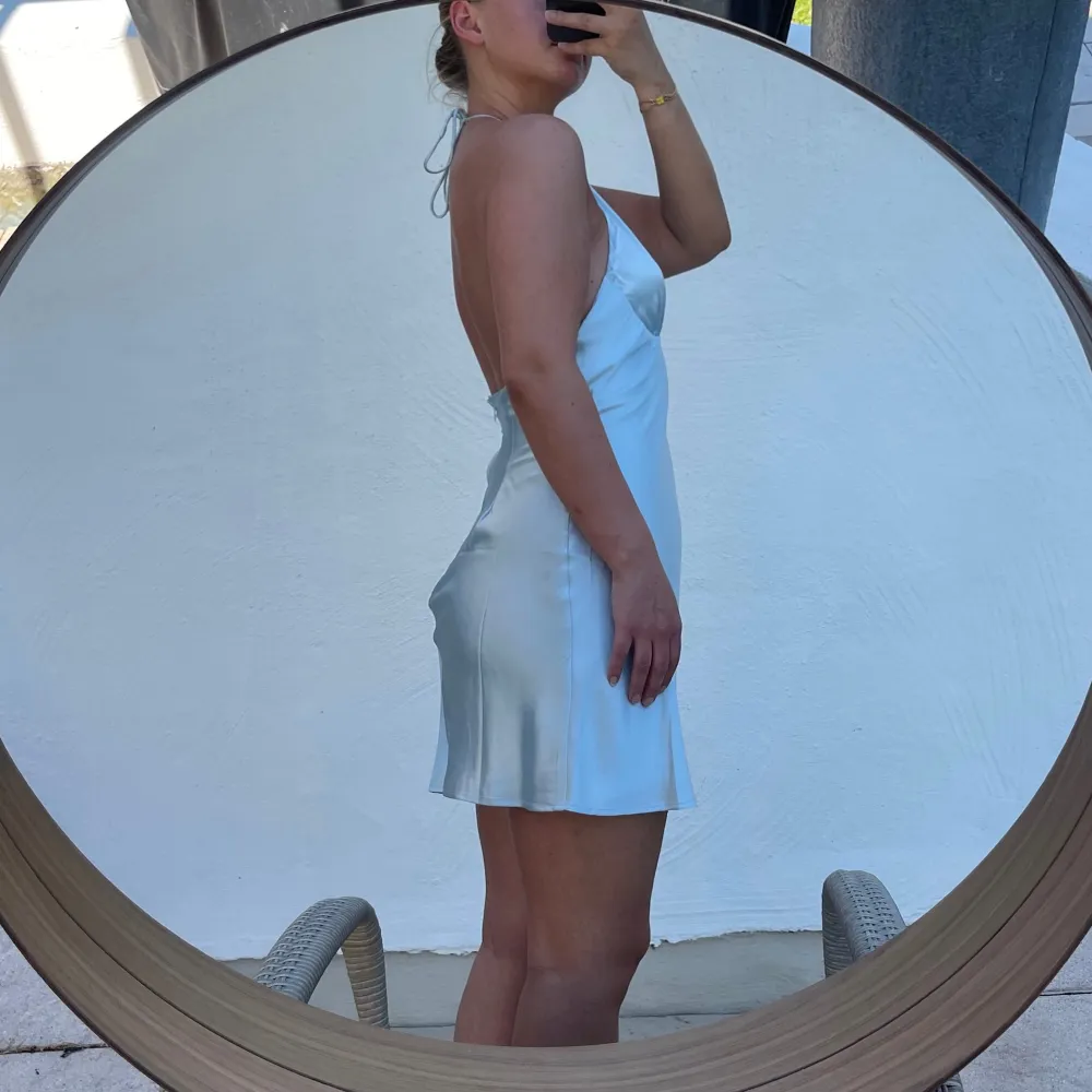 Säljer en superfin ljusblå klänning i satin. Den har en snygg halterneck-design som ger en elegant look. Perfekt för sommarens fester eller en dag på stan. Klänningen är kort och har en smickrande passform. Liten i storleken 🩵. Mekot.