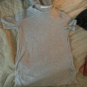 Grå t-shirt från & Other Stories - Säljer en stilren grå t-shirt från & Other Stories. Den är kortärmad och tillverkad i mjukt bomullsmaterial, perfekt för en avslappnad look. Passar bra till jeans eller kjol för en enkel och snygg outfit.