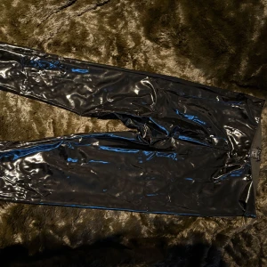 Svarta glansiga byxor från Avvisu - Snygga svarta glansiga byxor från Avvisu. De har en tight passform och är perfekta för en trendig look. 