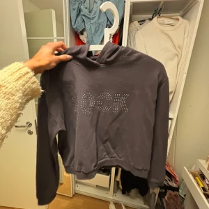 Mörkgrå/brun/svart hoodie från Destination - Säljer en cool mörkgrå hoodie från Destination med texten 'ROCK' i glittriga stenar på framsidan. Hoodien är croppad och har långa ärmar, perfekt för en avslappnad stil. Passar bra till jeans eller leggings. 🖤
