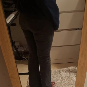 Grå byxor från Pull&Bear - Snygga svart-gråa byxor från Pull&Bear i en klassisk stil. Byxorna har en rak / flared passform och är perfekta för en avslappnad look. De är tillverkade i ett bekvämt material som ger en skön känsla hela dagen. De är ganska så små i storlek men också stretchiga samtidigt. Jag är storlek M men får de och passa fast de är lite stora runt midjan men de går att fixa med bälte. Säljer dessa jätte fina jeans på grund av att jag tycker att de är stora runt midjan. 