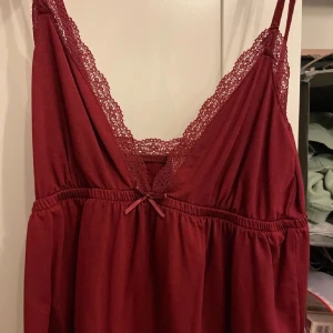 Vinröd topp med spetsdetaljer från Nelly - Säljer en vinröd topp från Nelly, aldrig använd. Säljer för att den är för stor på mig