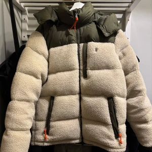 Beige teddyjacka från Polo Ralph Lauren - Använd väldigt sparsamt! Säljer en snygg beige teddyjacka från Polo Ralph Lauren med gröna detaljer. Jackan har en pufferdesign med dragkedja och hög krage. Perfekt för kyliga dagar med sin mysiga och varma stil. 🧥Den är slutsåld på många sidor och nypris är 6000 kr. Kvitto finns 