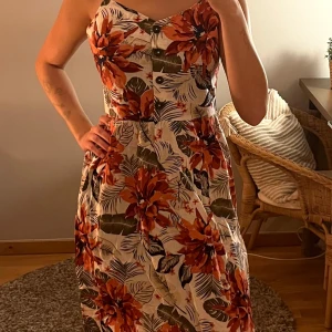 Blommig klänning - Sommarklänning med knappar och blomster mönster på! Klänningen är i linne och bomull vilket gör den luftig och passformen blir väldigt fin! Längdvis så hamnar den lite under mitten av låret på mig (jag är 174 cm lång). Har använts fåtal gånger, men i väldigt fint skick! Alla använda plagg som säljs tvättas noga innan leverans! Det är bara att skriva om du har några frågor! <3