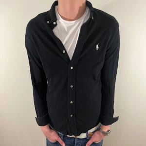 Svart Ralph Lauren skjorta - Nu säljer vi ännu en fet polo skjorta som passar till alla tillställningar och skjortan är i mycket bra skick! Du ska kunna uttrycka stil utan att det kostar för mycket!🕺🍾💼🤩  Storlek👔: S Nypris💰: ca 1499 kr