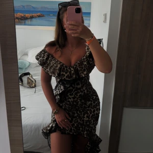 Leopardmönstrad klänning med volangdetaljer - Trendig leopardmönstrad klänning med volanger och offshoulder-design. Perfekt för en kväll ute eller en speciell tillställning. Klänningen har en smickrande passform och är både stilren och iögonfallande.