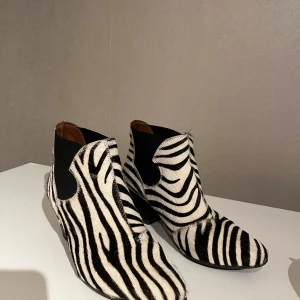 Zebramönstrad boots -  Boots med zebramönster i svart och vitt. De har en spetsig tå , klack och är bekväma .Tillverkade i ett material som liknar päls. 