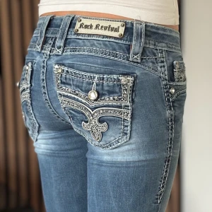 Rock revival jeans - Lågmidjade bootcut jeans från rock revival. Snygg design. Okej skick, se bild. Mått: Innerbenslängd: 83cm   Midjemått rakt över: 36cm Modellen är 166cm lång. Fler bilder finns. Skriv gärna ifall du har några frågor! 💗 OBS se färg fläckar på byxornas framsida