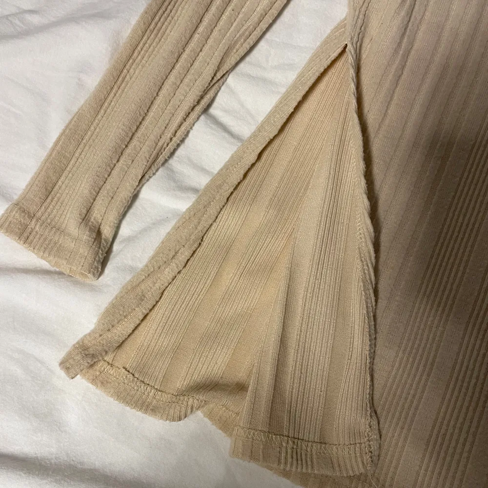 En beige långärmad längre tröja som har ränder på sig. Den har även öppningar på båda sidorna!!😍. Neuletakit & Villapaidat.