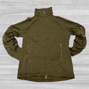 Houdini kofta - Säljer en olivgrön fleecejacka från Houdini med dragkedja framtill och två praktiska fickor med dragkedjor. Jackan har en hög krage och är perfekt för kyligare dagar. Den är tillverkad i mjukt och bekvämt fleecematerial.