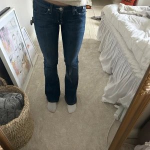 Blå bootcut jeans från Rock & Republic - Snygga blå bootcut jeans från Rock & Republic med klassisk femficksdesign och subtila slitningar. Perfekta för en avslappnad stil med en touch av elegans. Passar bra till både sneakers och klackar.