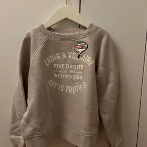 Beige/grå collegetröja från Zadig & Voltaire - Collegetröja från Zadig&Voltaire, beige/grå med tryck på bröstet. Stl ca 10 år
