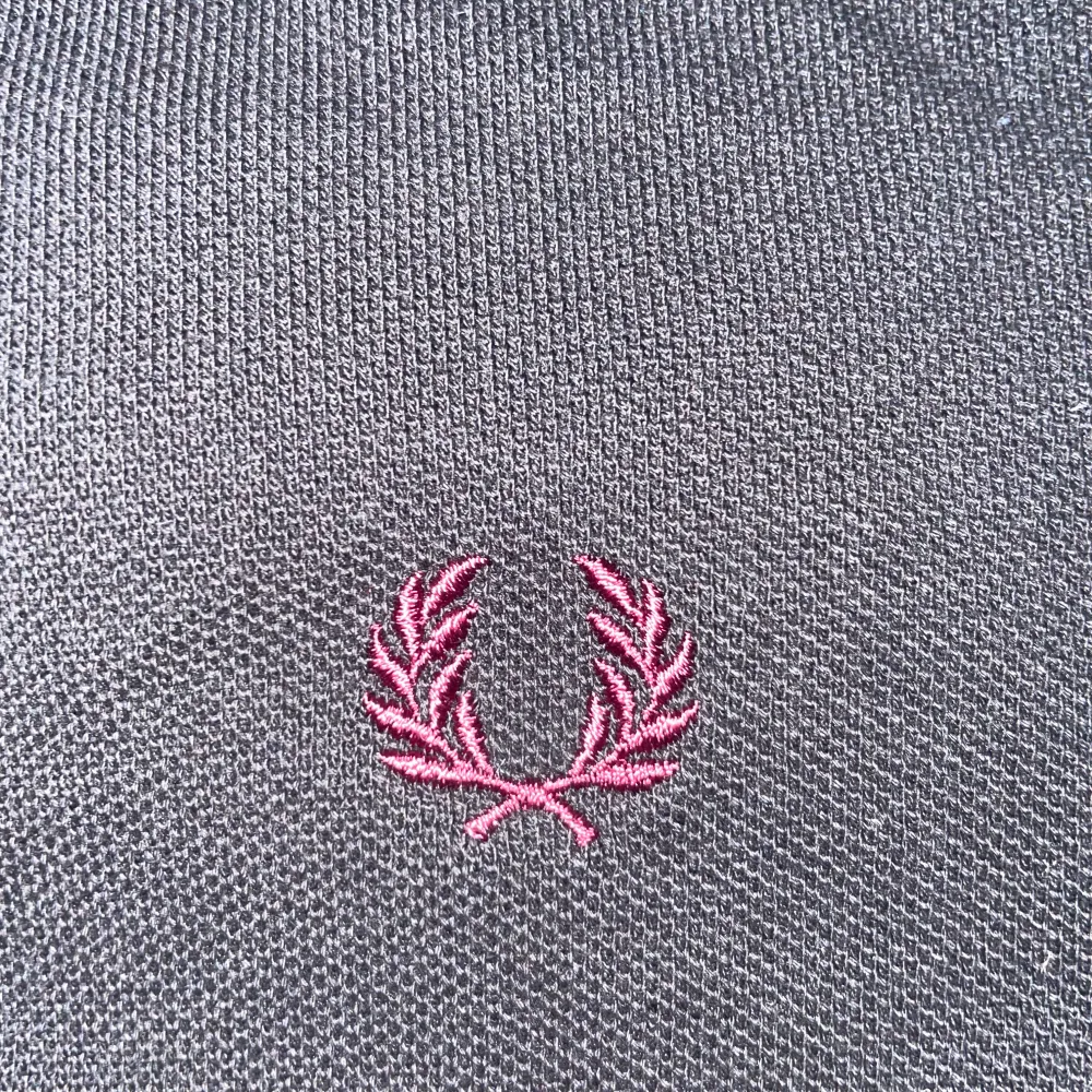 Säljer en snygg svart pikétröja från Fred Perry i storlek M. Tröjan har en klassisk design med korta ärmar och en broderad logga på bröstet. Den har vita och röda ränder på kragen och ärmsluten, vilket ger en stilren look. Sparsamt använd.. T-shirts.