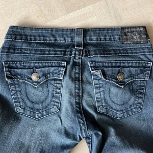 True religion jeans - Vet ej vilken modell, men mycket lowwaist och bootcut. Jeansen är smått slitna längst ner och har en söm som har gått upp ngt, men inget märkbart och annars i bra skick. Midjemått: 80cm, Innerbenslängd: 84cm, Bootcut bredd: 22cm.