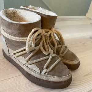 Bruna vinterboots från Inuikii - Säljer ett par snygga och varma vinterboots från Inuikii. De är i en fin beige/brun färg med en mysig pälsfodring på insidan. Skorna har spruckit lite i lädret (se sista bilden) nypris är 2999 kronor och är köpta år 2022💛