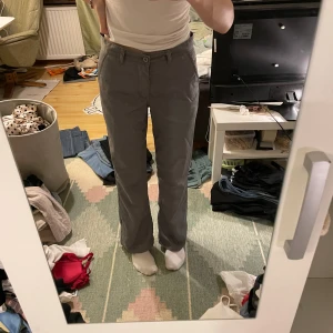 Grå byxor från Sacramento Jeans - Säljer ett par grå byxor från Sacramento Jeans. De har en rak passform och är midwaist med knappar framtill. Perfekta för en avslappnad stil eller vardagsbruk. Passar bra till både t-shirt och skjorta.