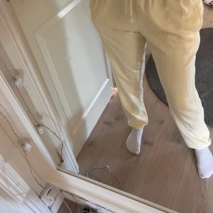 Beige mjukisbyxor - Säljer ett par superbekväma gula mjukisbyxor. Perfekta för en chill dag hemma eller när du bara vill vara bekväm. De har en dragsko i midjan för bästa passform och är gjorda i ett mjukt material. Passar perfekt till en avslappnad stil!
