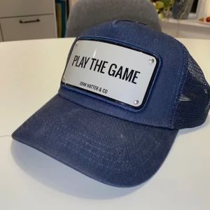 John Hatter keps - John hatter keps med citat ”Play The Game”. Använd fåtal gånger men legat i kartongen därav är den dammig.. Nytvättad nu, allt og medföljer. Gratis frakt, mvh Elias 
