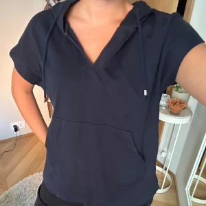 Marinblå kortärmad hoodie - Marinblå kortärmad hoodie som är så cool, har luva och slittar på varje sida.